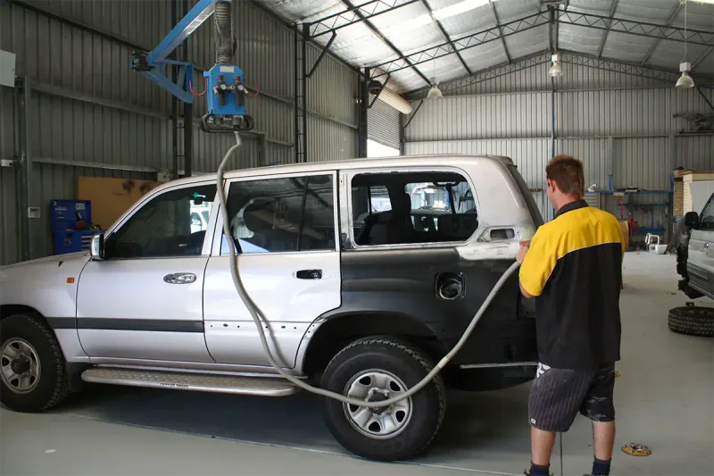 Auto body technician spay painting undercoat on back panel of vehicle